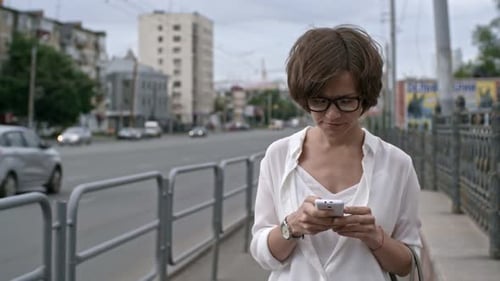 Woman Walking along Street with Smartphone