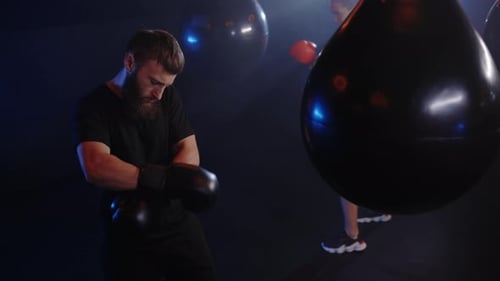 Bearded Man Putting on Boxing Gloves in Gym