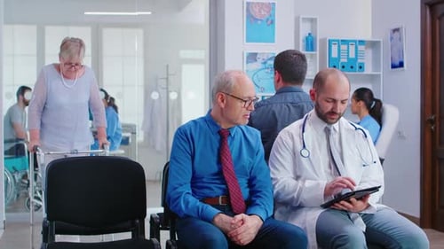 Doctor Explaining Test Results to Senior Man in Hospital Waiting Area