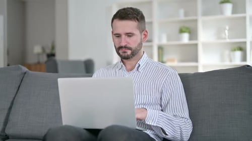 Man working on laptop while sitting on couch