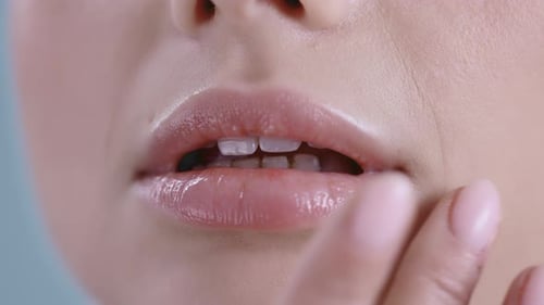 Nahaufnahme einer jungen Frau, die ihre Lippen berührt