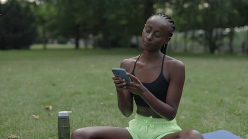 Woman Using Smartphone While Sitting on Yoga Mat