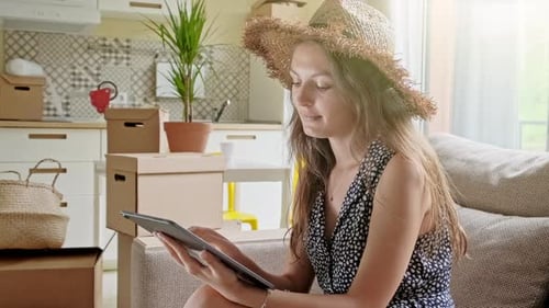 Woman Using Tablet Among Moving Boxes in Home