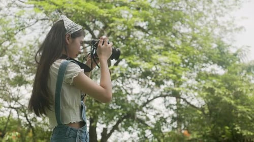 Beautiful happiness young asian woman using camera take a photo for relax in the park.