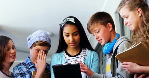 Gruppe von Schulfreunden nutzt digitales Tablet im Korridor