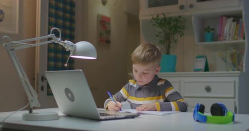 Child Doing Schoolwork at Desk With Laptop