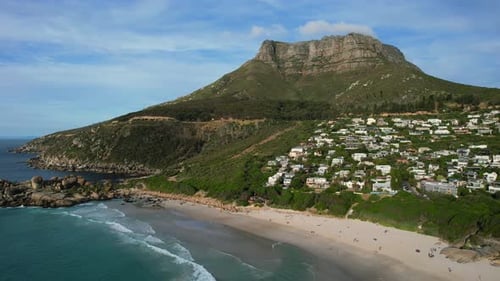 rocky coastline of Llandudno Beach and Table Mountain at sunset in Cape Town, aerial