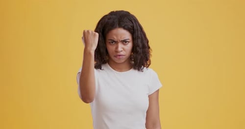 Woman Raising Her Fist in Defiance Against Yellow