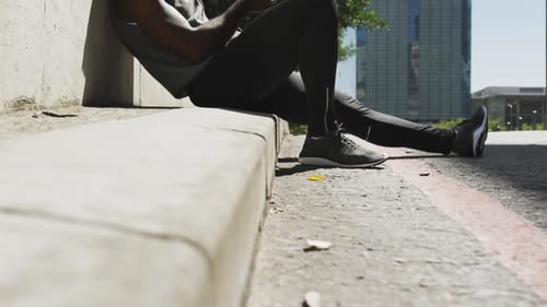 Athletic Man Relaxing, Using Phone in City