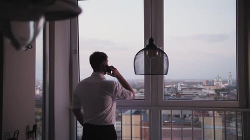 Man Talking on Phone in City Apartment