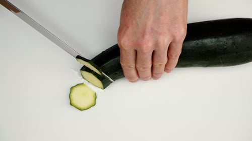 Cutting Fresh Zucchini with a Knife on White Board
