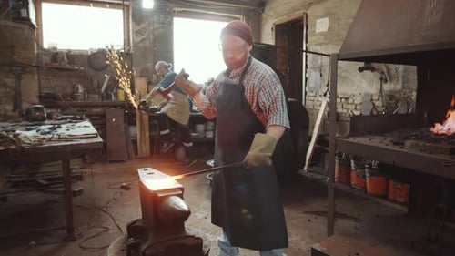 Two Blacksmiths Using Hammer and Cutting Wheel in Workshop