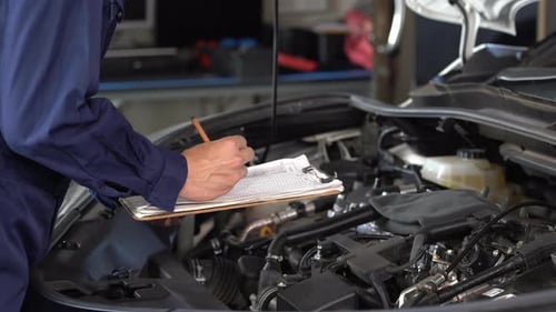 mechanic hand checking and repair service a car with clipboard