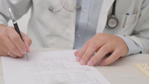 Arzt mit einem Stethoskop am Hals schreibt auf ein weißes Papier. nahaufnahme