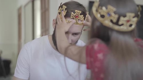 Girl Puts Crown on Father's Head at Home