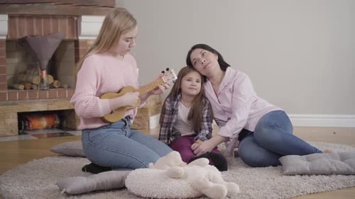 Woman and Child Listen to Ukulele Music