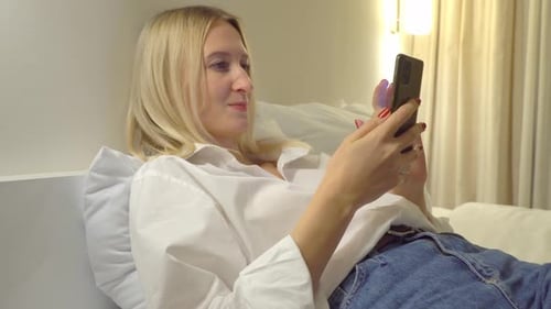 Woman Using Smartphone Relaxing on Bed