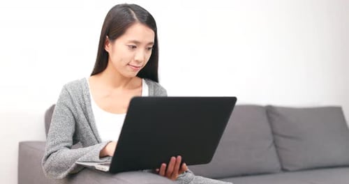 Woman Using Laptop on Couch Indoors