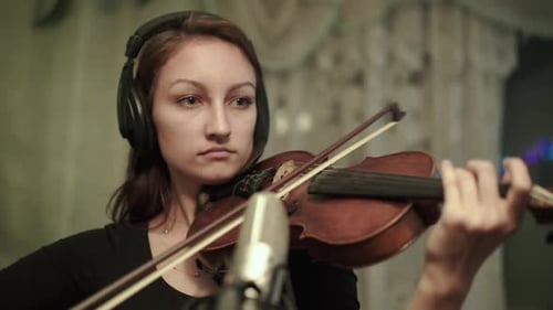 Woman Plays Violin with Headphones in Studio