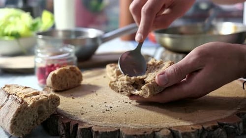Man Spreads Topping on Fresh Bread in Kitchen