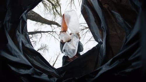 Dropping Plastic Bottles into Black Trash Bag