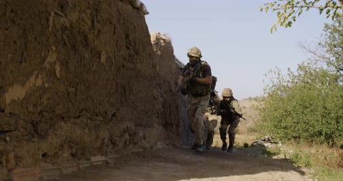 Camouflaged Soldiers walking along path in Rural Setting