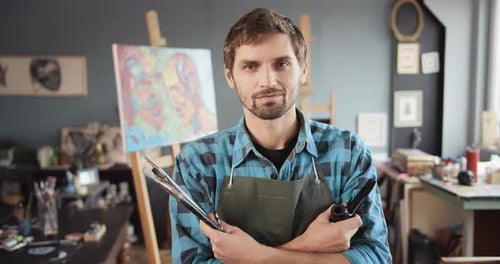 Male Artist Holding Brushes in Studio Portrait