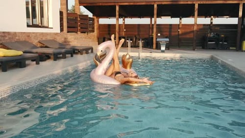 Jovem feliz com flamengo rosa flutuando na piscina