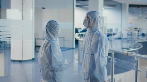 Medical Workers Talking Wearing Hazmat Suits And Masks In Clinic