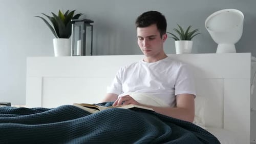 Man Reading Book in Bed