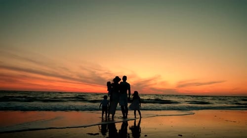 Silhouetted Happy Family Stand on the Beach at Sunset