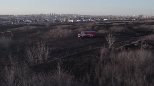 Firetruck Drives Across Burnt Field in Daylight