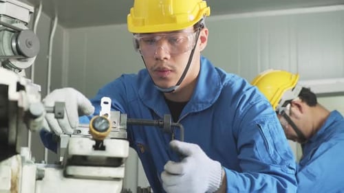 Three Factory Workers Repairing Machinery at Machine Shop