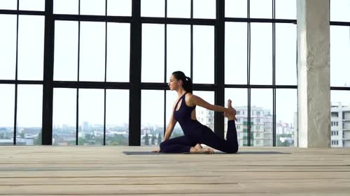 Young athletic girl doing sports in modern studio with big windows