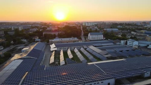 Aerial View of Blue Photovoltaic Solar Panels Mounted on Industrial Building Roof for Producing