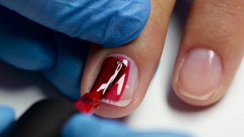 Manicurist Does Nail By Red Varnish. Close Up