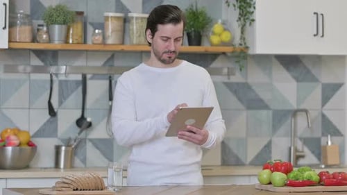 Man Using Tablet in his Home Kitchen