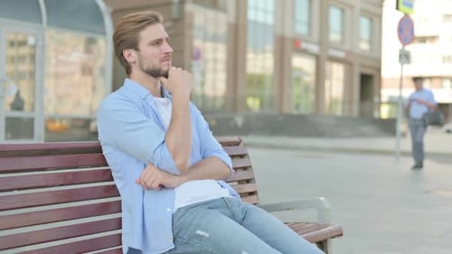 Man Thoughtfully Sitting on a Bench in the City