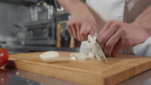 Hands Chopping Onion on Wooden Board in Kitchen