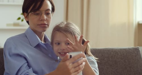 Woman and Girl Use Smartphone on Couch
