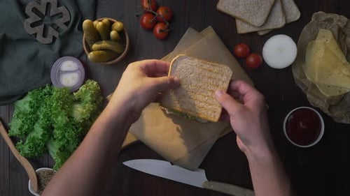 Flat Lay of the Sandwich with Ham and Salad on the Wooden Board in the Beam of Light, Chef's Hand