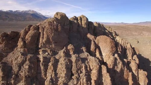 Aerial panning view of rocky desert mountain in vast landscape
