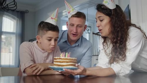 Boy Blows Out Birthday Candles With Family