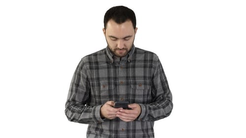 Young man walking and using a smartphone on white background.