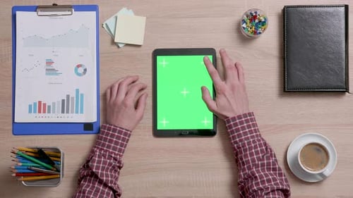 Top View of a Man Tap Multiple Times on the Right Top Corner of a Green Screen on Tablet