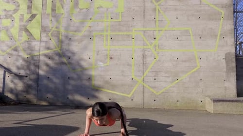 Jeune femme faisant des exercices burpee routine pendant que vous vous entraînez à l'extérieur