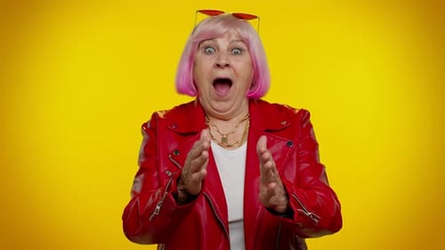Stylish Senior Woman Expressing Shock on Yellow Background
