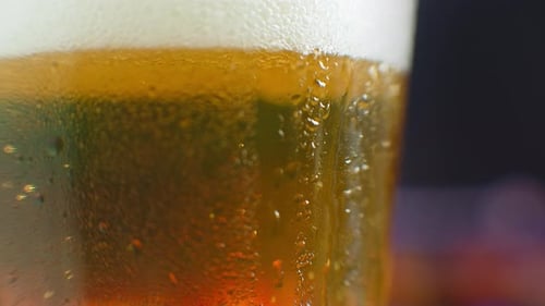 Macro Shot of a Drop Running Over a Glass of Beer. Sweat on a Cold Glass of Beer. A Dripping Drop on