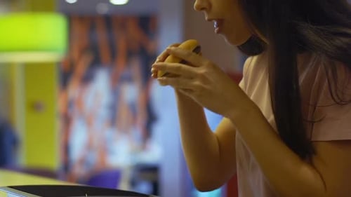 Woman Enjoys a Hamburger in a Bright Restaurant