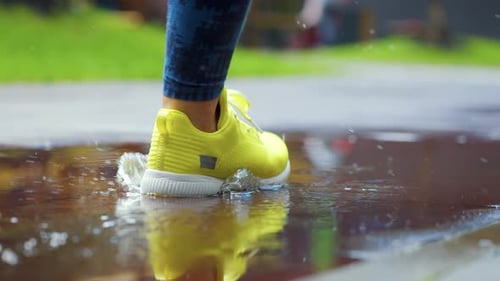 Female Sports Woman Jogging Outdoors Stepping Into Puddle